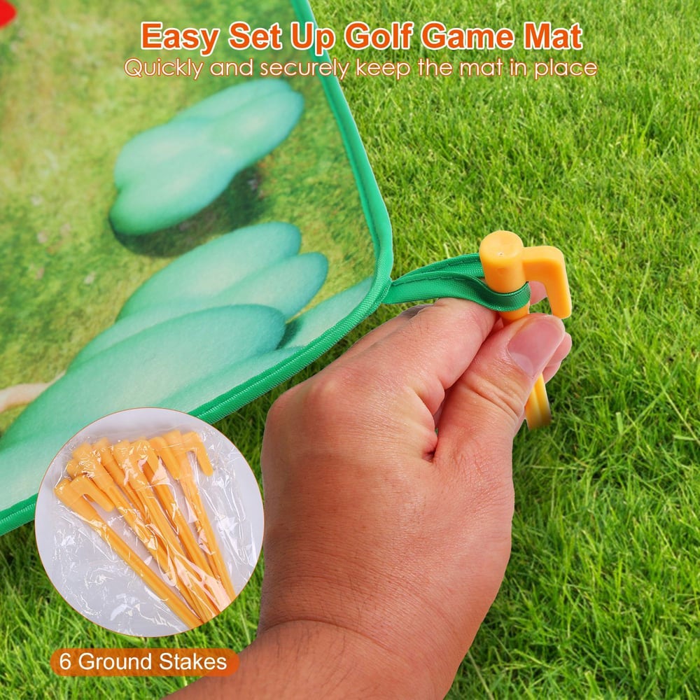 Hand holding a yellow ground stake to secure a colorful golf game mat on grass, with a close-up of additional stakes in the lower left corner.