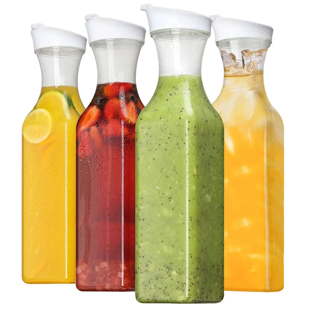Four transparent glass bottles filled with colorful beverages, including lemon-infused water, mixed fruit tea, green smoothie, and iced tea, all with white lids.