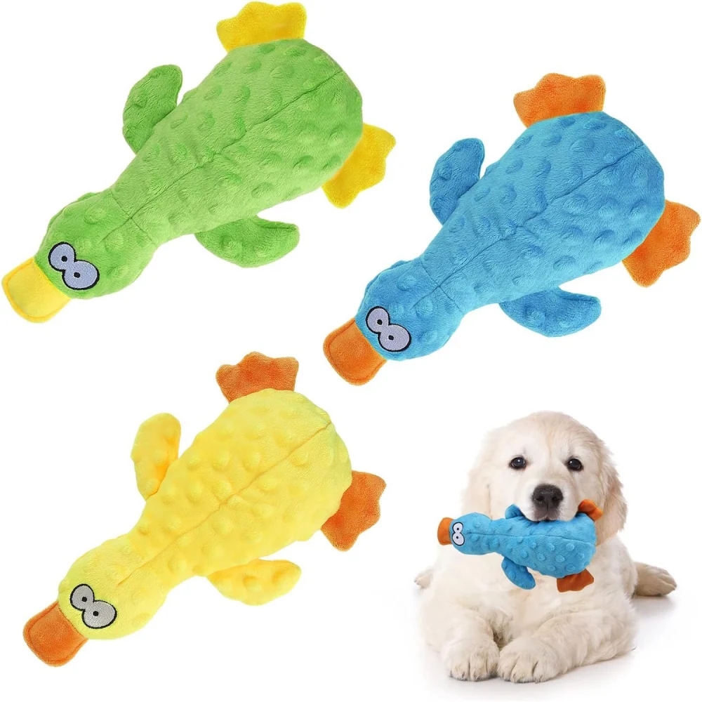 Colorful plush duck-shaped dog toys in green, blue, and yellow, with a golden retriever puppy happily holding the blue one.