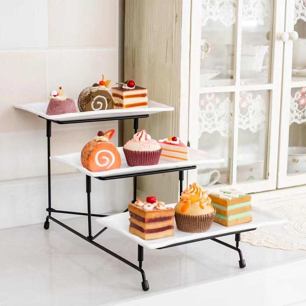 Three-tiered dessert stand displaying colorful cakes and pastries, including cupcakes, layered cakes, and fruit-topped treats, set against a charming kitchen backdrop.