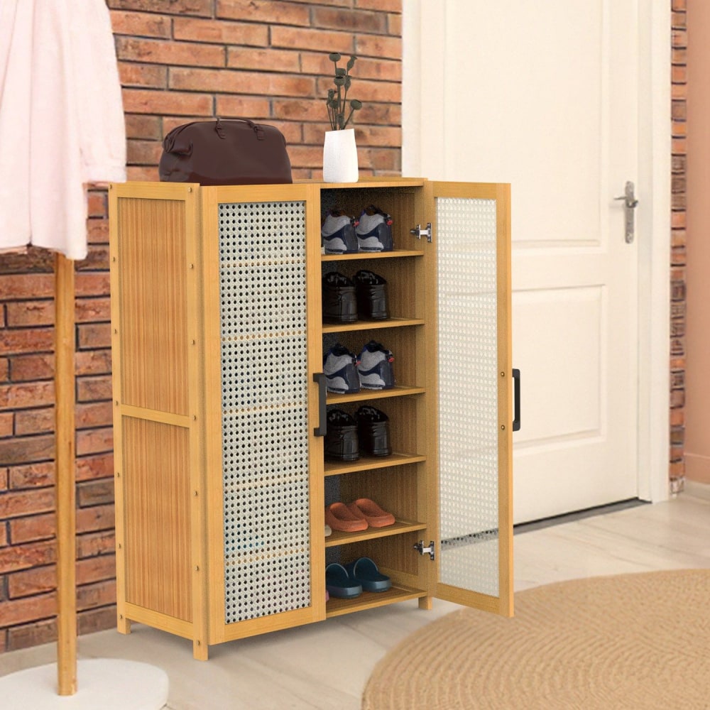 Modern wooden shoe storage cabinet with mesh doors, featuring multiple shelves filled with various shoes and a stylish handbag on top, set in a cozy entryway with brick walls.