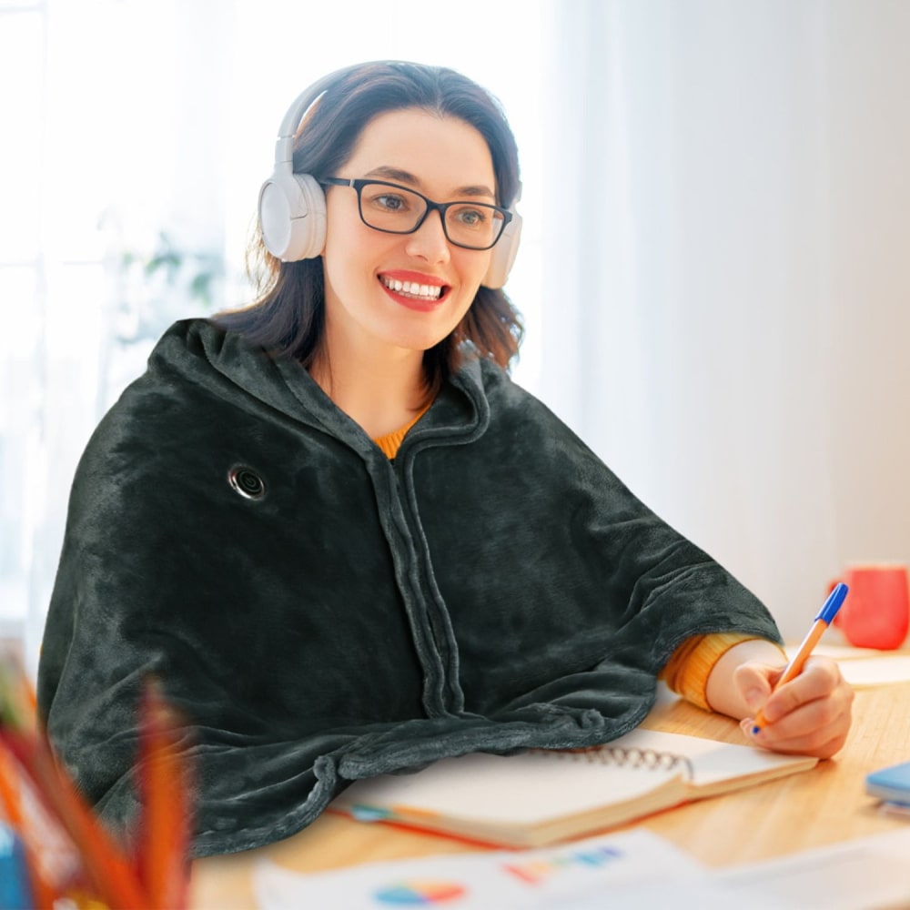Cozy grey heated blanket shawl worn by a person with headphones, sitting at a desk surrounded by stationery and notebooks in a bright indoor setting.