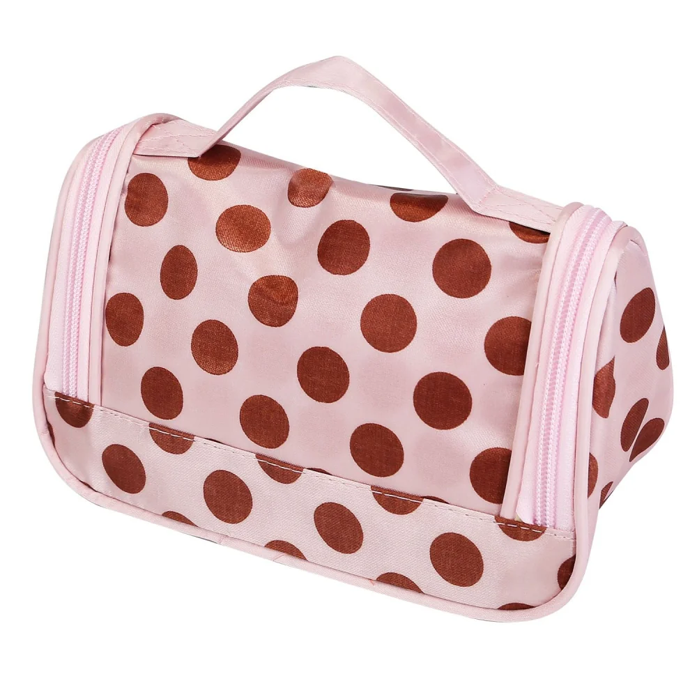 Pink cosmetic bag with brown polka dots and a zip closure, featuring a top handle for easy carrying.