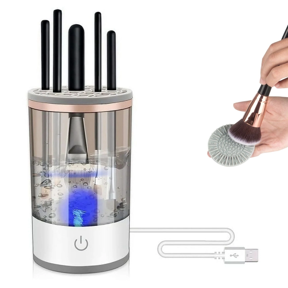 Electric makeup brush cleaner with USB charging, featuring a transparent water tank, LED light, and a hand holding a makeup brush above a cleaning pad.