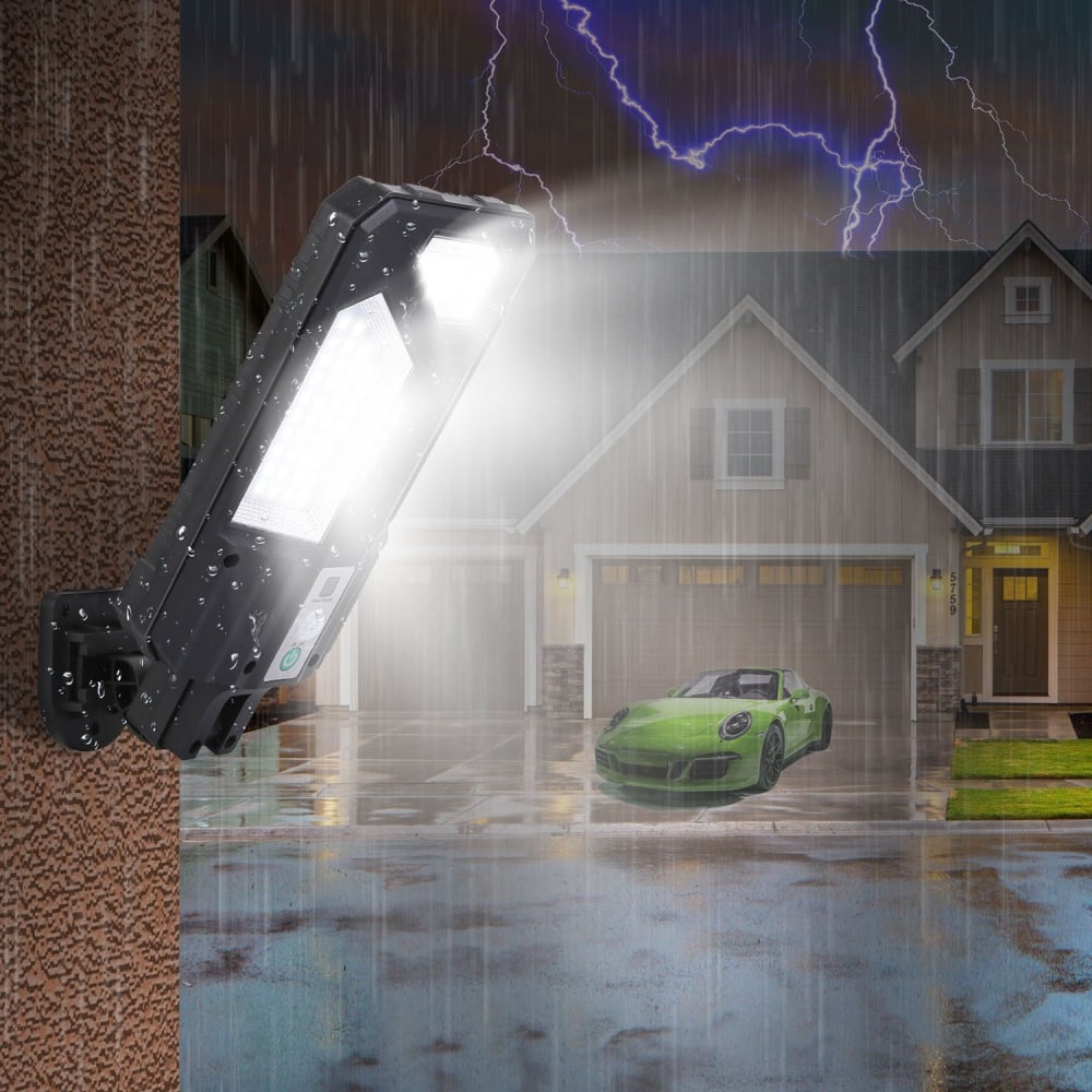 LED solar-powered security light illuminating a driveway during a rainstorm, with a modern home and a green sports car in the background.