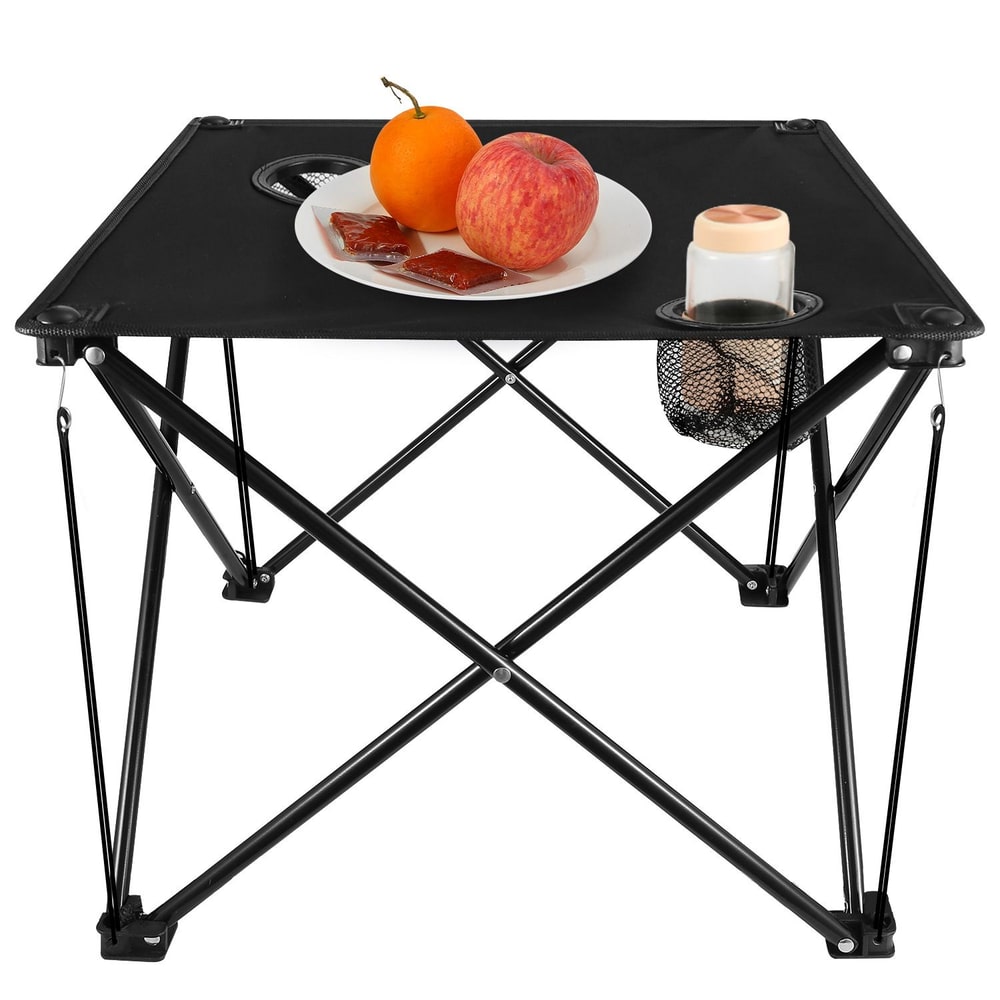 Portable folding table with black surface, featuring a plate of an apple and an orange, along with packets of sauce, and a cup in a holder, ideal for outdoor dining or picnics.